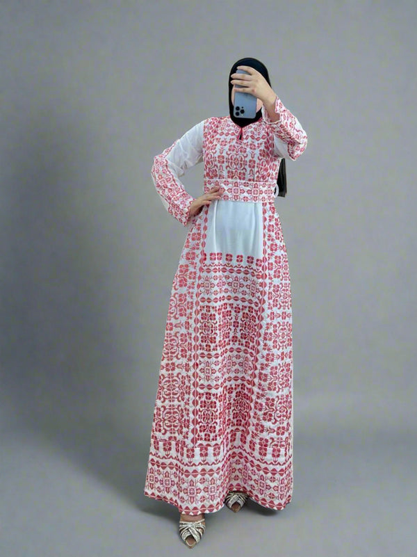 Woman wearing a white Palestine Saudi Crepe Dress with traditional red Ethamine embroidery, full-length modest design, photographed indoors at Dinar Shop